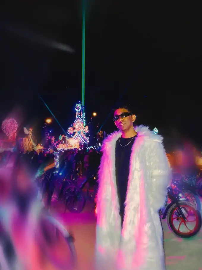 Elius in a white fur coat under festival lights